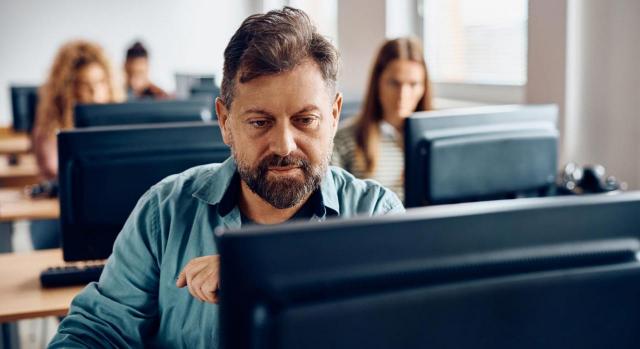 Vídeos educativos sobre el Estándar Voluntario de Informes de Sostenibilidad para pymes no cotizadas. Hombre de mediana edad trabajando en un ordenador de mesa